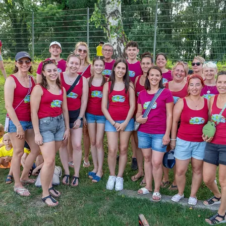 Eine Gruppe von Frauen und Mädchen in passenden roten Shirts und Jeansshorts posiert für ein Foto im Park.
