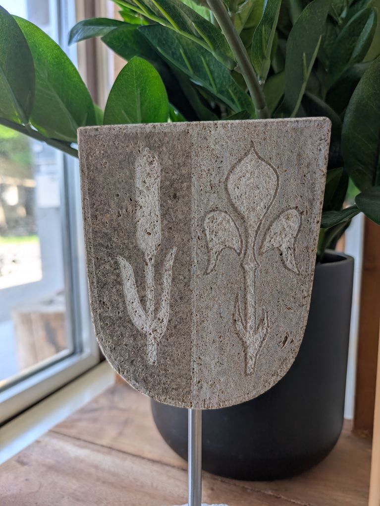  Abschnitt Bild: Eine Betonplatte mit Fleur-de-Lis-Design vor einer grünen Topfpflanze in der Nähe eines Fensters.