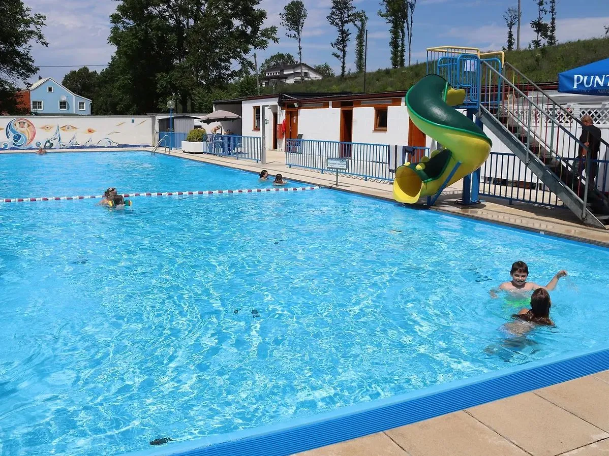 Kinder schwimmen in einem Schwimmbad in einem Park mit einem gelben und grünen Rutschvergnügen.