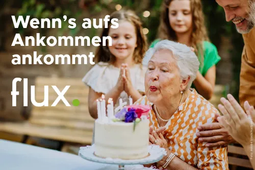 Eine ältere Frau feiert ihren Geburtstag umgeben von Familie, mit einem Kuchen und Kerzen auf einem Tisch. Der Text lautet 'Wenn's aufs Ankommen ankommt flux'.