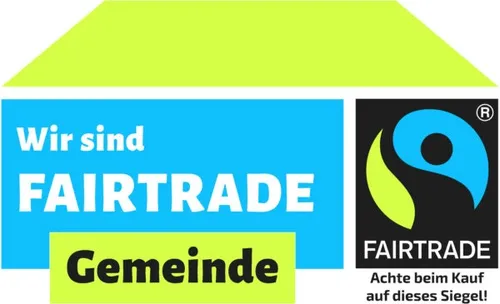 Das Bild zeigt einen blau-grünen Hintergrund mit weißem Text, der 'Wir sind FAIRTRADE Gemeinde' lautet. Rechts befindet sich ein schwarzes und blaues Logo mit dem Wort 'FAIRTRADE'. Darunter steht 'Achte beim Kauf auf dieses Siegel!', was bedeutet, dass man beim Kauf auf dieses Siegel achten sollte.