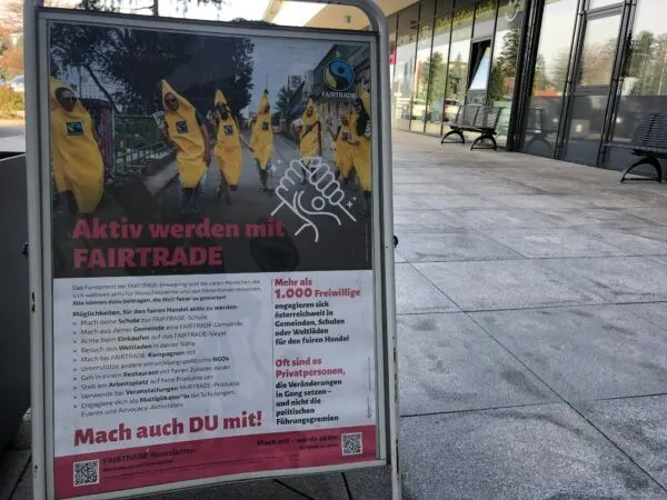 Ein Plakat zeigt eine Gruppe von Menschen in gelben Kostümen mit den Worten 'Aktiv werden mit FAIRTRADE' und ermutigt zur Teilnahme. Es erwähnt über 1.000 Freiwillige und Privatpersonen, die die Bewegung unterstützen.