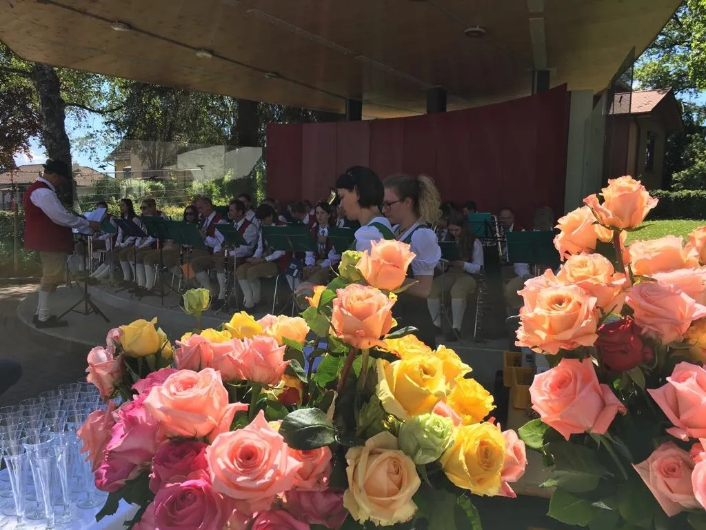 Eine Band spielt auf der Bühne mit roten Vorhängen im Hintergrund, und ein Rosenstrauß ist im Vordergrund.