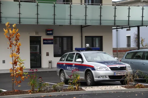 Ein Polizeifahrzeug mit dem Kennzeichen BP 6070 ist vor einem Polizeigebäude geparkt. Das Gebäude hat Glaswände und einen Balkon über dem Eingang.