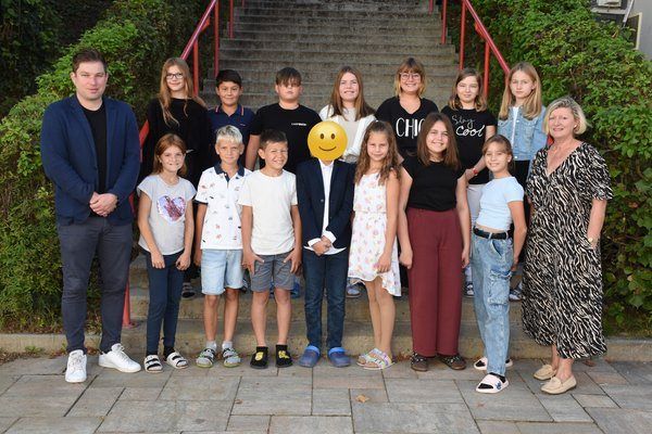Eine Gruppe von Menschen posiert für ein Foto vor einer Treppe. Sie tragen verschiedene Kleidungsstücke und Schuhe. Die Menschen lächeln und posieren für die Kamera.