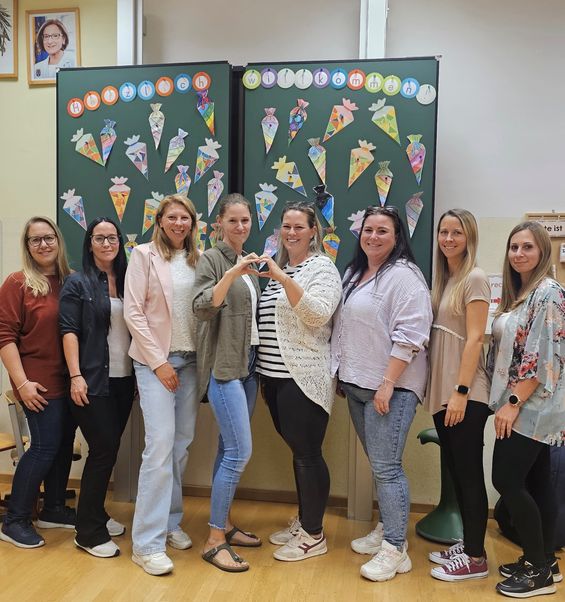 Eine Gruppe von Frauen posiert für ein Foto vor einer dekorierten Pinnwand mit bunten Eistüten.