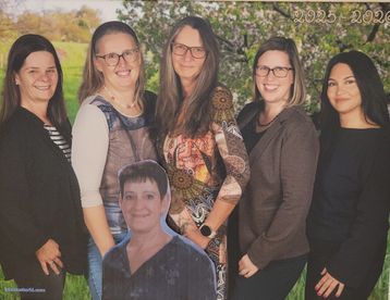 Fünf Frauen stehen in einer Reihe, lächelnd, in einem Park mit einem Baum und einem Feld im Hintergrund. Eine Frau trägt eine Halskette und eine Brille, und das Foto ist auf 2025 datiert.