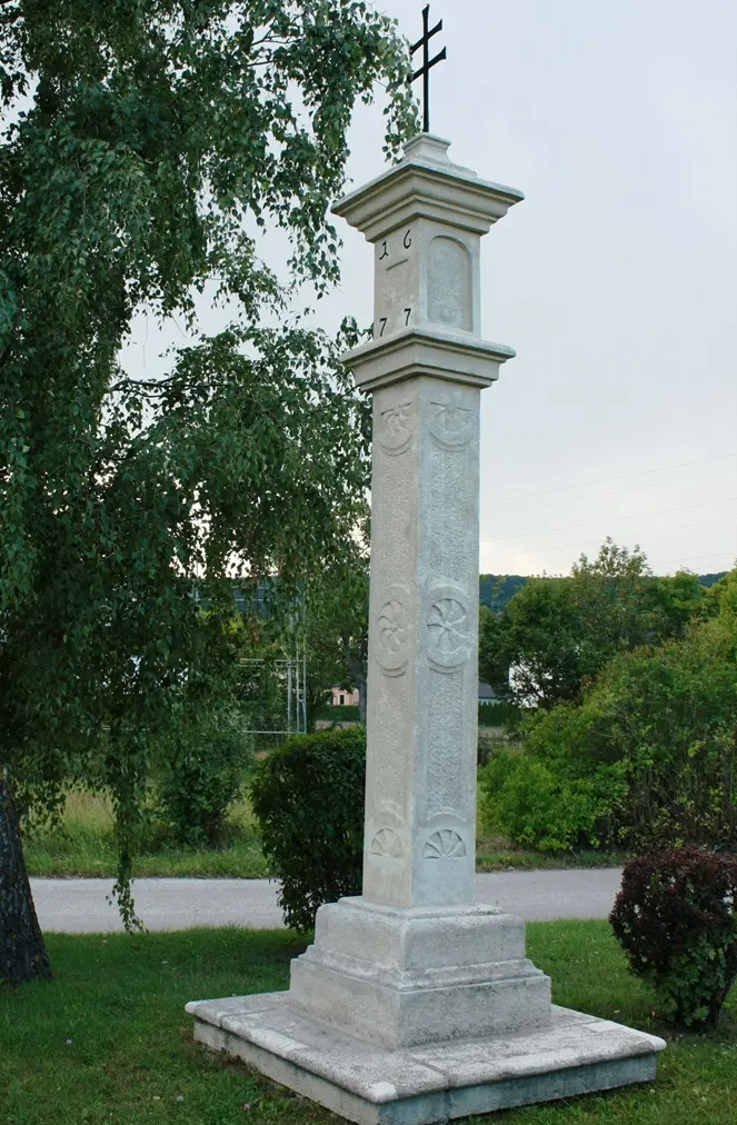 Ein hoher, gravierter Steinpfeiler mit den Zahlen 1, 6, 4, 7 und 7 steht in einem Park.