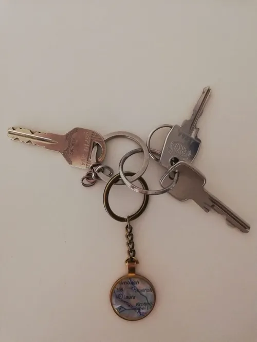 Vier Schlüssel sind auf einem weißen Hintergrund abgebildet. Die Schlüssel haben unterschiedliche Längen und sind an Schlüsselringen befestigt. Ein Schlüsselanhänger mit Kartendesign ist ebenfalls enthalten.