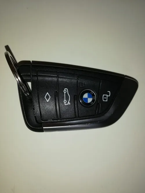 Ein schwarzer BMW-Autoschlüssel mit BMW-Logo und vier Tasten. Eine Taste ist mit 'M' beschriftet.