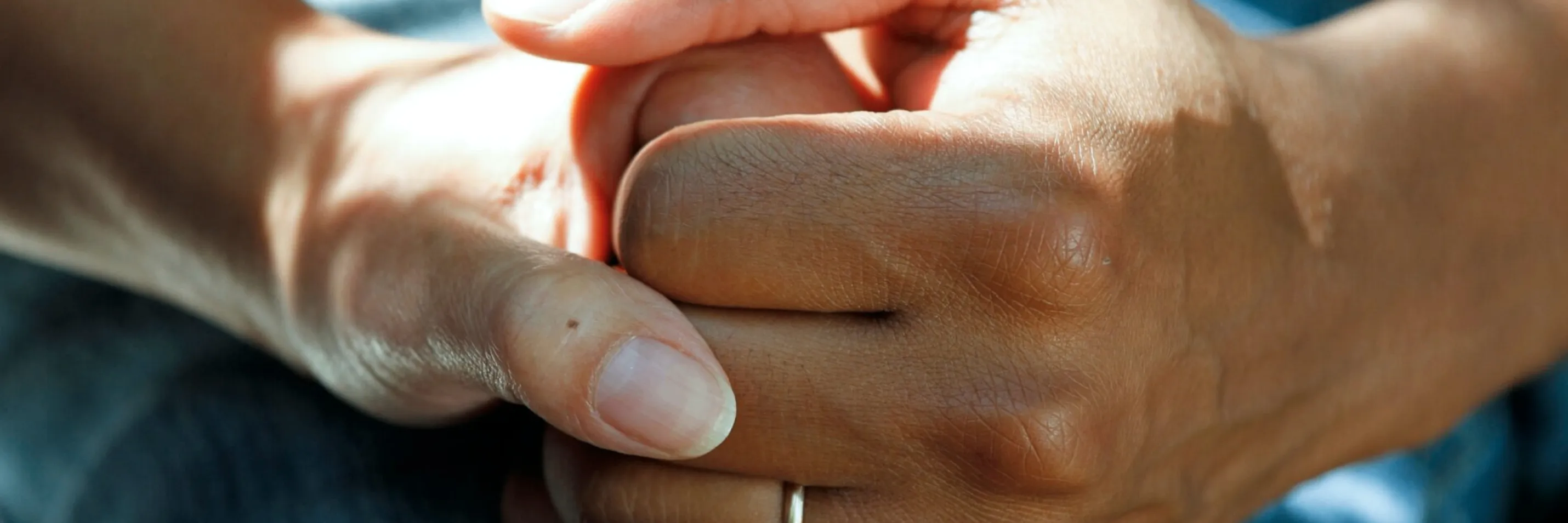 Ein Nahaufnahme einer Hand, die einen Fingerzeig mit einem kleinen schwarzen Fleck zeigt, gehalten von einer anderen Hand. Die Hauttextur ist sichtbar, und es gibt einen silbernen Ring am Finger.