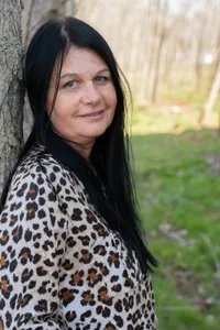 Eine Frau in einem Leopardenmuster-Oberteil posiert für ein Foto im Freien auf einem Feld.