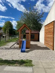 Ein Spielplatz mit einer blauen Rutsche und einem hölzernen Spielhaus.
