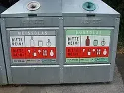 Ein Recyclingbehälter mit zwei Fächern. Jedes Fach hat ein Schild mit einer Warnung, es sauber zu halten, zusammen mit Symbolen für verschiedene recycelbare Gegenstände. Das obere Fach hat ein blaues Schild mit dem Wort 'Weissglas', während das untere Fach ein grünes Schild mit dem Wort 'Blauglas' hat.