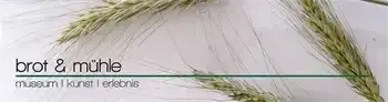 Ein Nahaufnahmebild von Weizenähren mit grünen Blättern vor weißem Hintergrund. Der Text 'brot & mühle' ist in schwarzer Schrift geschrieben. Darunter steht 'museum | kunst | erlebnis' in grün. Das Bild ist mit einer dünnen grünen Linie eingefasst.