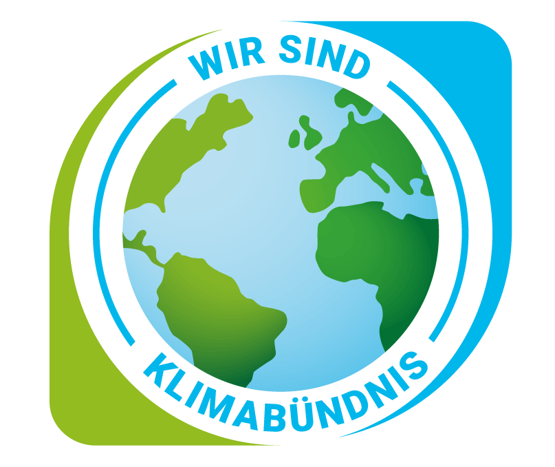 Das Bild zeigt ein Logo mit einer Erdkugel und dem Text 'WIR SIND KLIMABUNDNIS'. Das Design ist kreisförmig mit einem blauen und weißen Rand.
