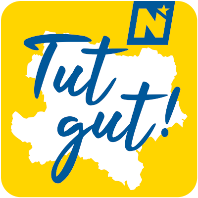 Gelber Hintergrund mit einer weißen Karte einer Region. Blauer Text 'Tut gut!' erscheint über der Karte. Ein 'N' mit einem Stern ist in der oberen rechten Ecke.