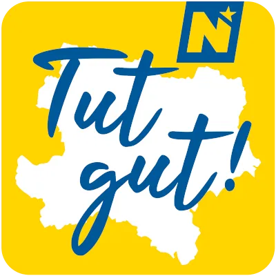 Gelber Hintergrund mit einer weißen Karte einer Region. Blauer Text 'Tut gut!' erscheint über der Karte. Ein 'N' mit einem Stern ist in der oberen rechten Ecke.