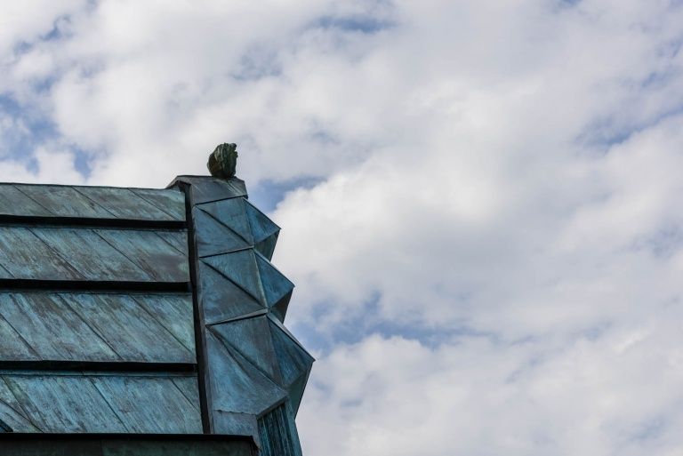 Eine Nahaufnahme eines Gebäudes mit einem geometrischen Musterdach unter einem blauen Himmel mit Wolken.