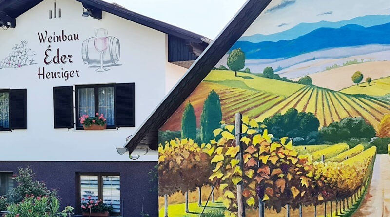 Ein Haus mit einem Wandbild von Weinbergen und Bergen. Es steht Weinbau Eder Heuriger an der Wand.