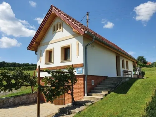 Ein kleines Haus mit rotem Dach und Ziegelwänden steht auf einem Hügel, mit Stufen, die zur Vordertür führen.