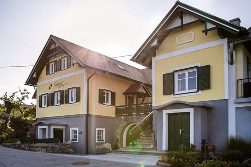 Zwei gelbe und graue Häuser mit Balkonen und Treppen. Das vordere Haus hat eine grüne Tür.