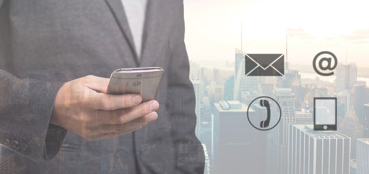 Ein Mann in einem Anzug hält ein Handy, mit einer Stadtsilhouette und Symbolen für E-Mail und Telefon im Hintergrund.
