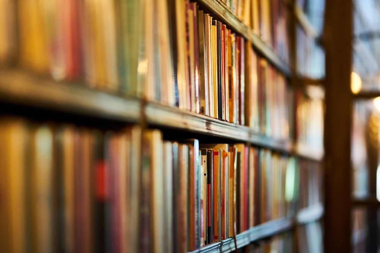 Nahaufnahme eines Bücherregals, gefüllt mit Büchern, einige scharf, andere unscharf, verschiedene Farben und Größen zeigend.