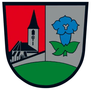 Ein heraldischer Schild, der durch eine vertikale Linie geteilt ist. Die linke Seite zeigt eine Kirche mit Turm und Uhr. Die rechte Seite zeigt eine stilisierte blaue Blume mit grünen Blättern.
