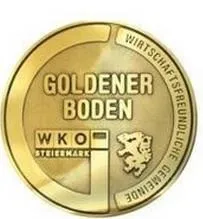 Eine goldene Münze mit 'GOLDENER BODEN' und 'WKO STEIERMARK' darauf. Das Logo ist ein Löwe mit einem Schild, und die Worte 'Wirtschaftskammer Steiermark' sind in einem Kreis darum herum.