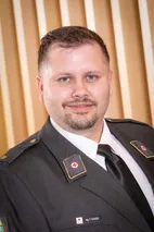 Ein Mann in Uniform mit einem roten Kreuz auf der Brust lächelt für die Kamera.