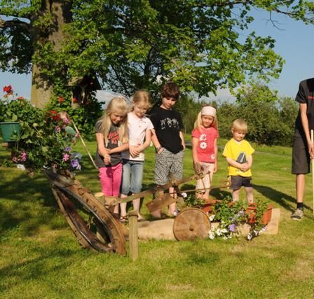 Eine Gruppe von Kindern und zwei Erwachsenen spielt Golf an einem sonnigen Tag in einem Park.