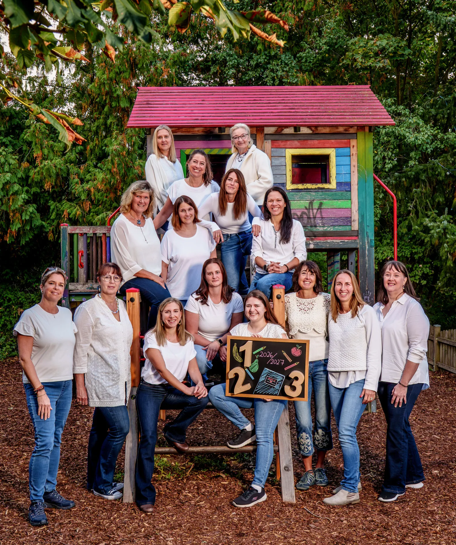 Eine Gruppe von Frauen posiert für ein Foto vor einem bunten Spielhaus.