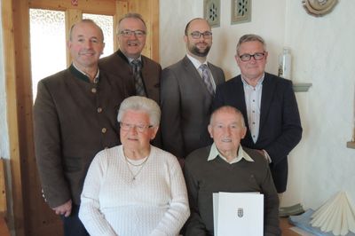 Eine Gruppe von sechs Personen, darunter ein älteres Paar, posiert für ein Foto. Der Mann rechts hält ein Zertifikat.