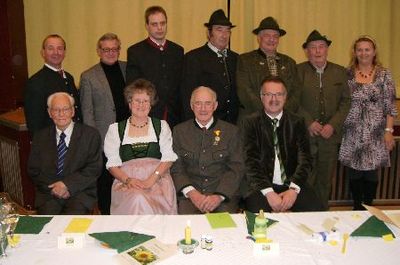 Eine Gruppe von Menschen in traditioneller Kleidung posiert für ein Foto an einem Tisch mit verschiedenen Gegenständen darauf.