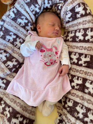 Ein Babymädchen schläft auf einer Decke mit einem rosa Hasenkleid und weißen langen Ärmeln.