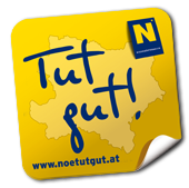 Ein gelber Aufkleber zeigt 'Tut gut!' mit einer Karte und einer Website-Adresse auf schwarzem Hintergrund.