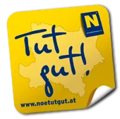 Ein gelber Aufkleber zeigt 'Tut gut!' mit einer Karte und einer Website-Adresse auf schwarzem Hintergrund.