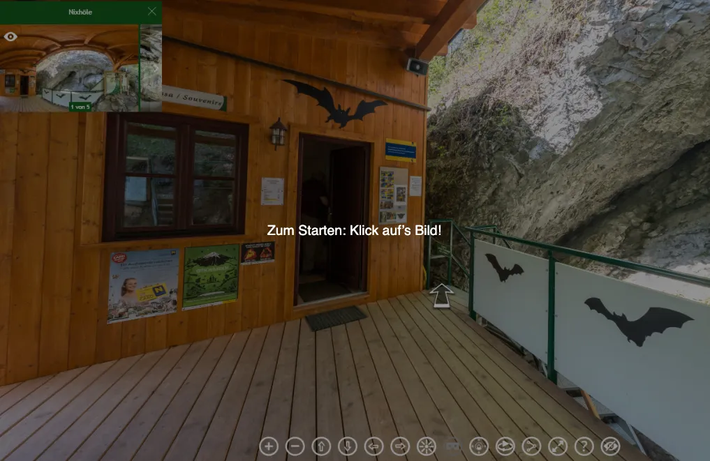Ein hölzerner Eingang mit einem Fledermaus-Logo. Ein Mann steht am Eingang. Ein Poster und ein Fledermaus-Logo an der Wand. Ein Balkon mit Geländer. Ein Berg und ein Fledermaus-Logo an der Wand.