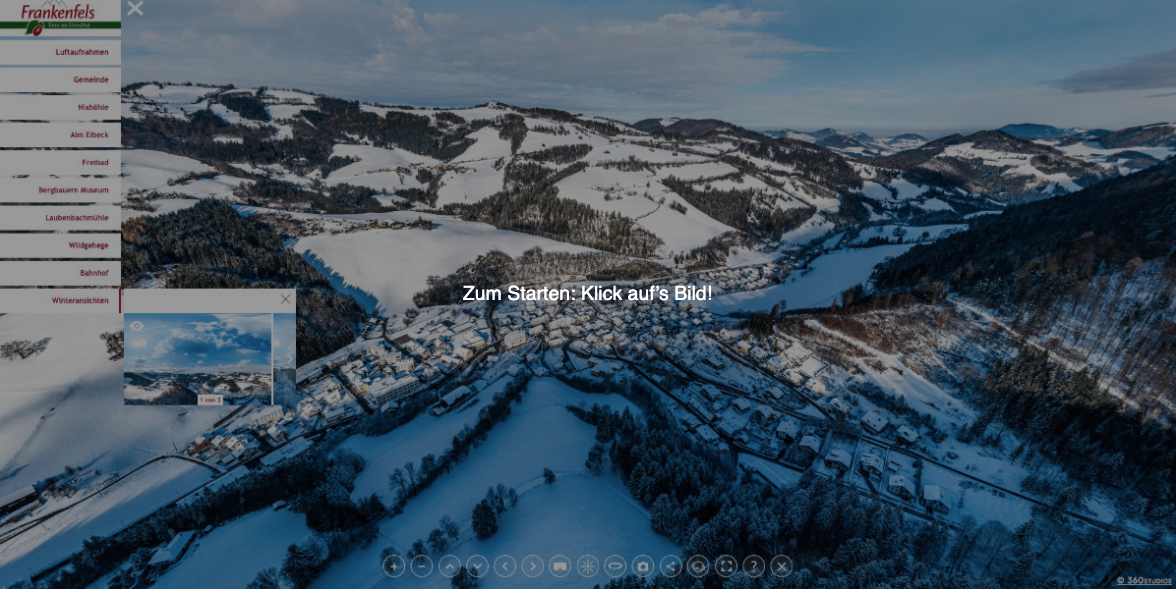 Schneebedeckte Landschaft mit Bergen und einer Stadt unten. Ein Hinweis lautet: 'Zum Starten: Klick aufs Bild!'