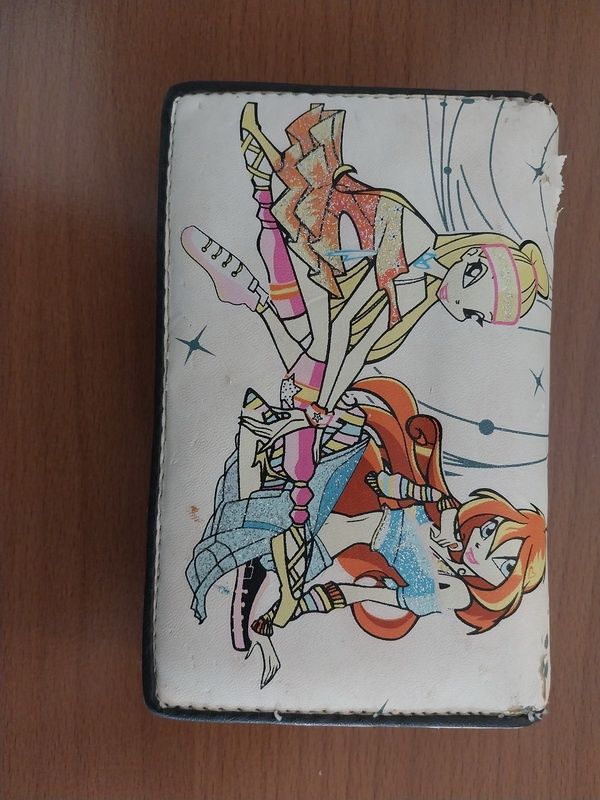 Ein weißes Portemonnaie mit bunten Zeichentrickfiguren auf einer Holzoberfläche.