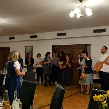 Eine Gruppe von Menschen in einem Speisesaal mit gelben Blumen, einer Tafel und einem Kronleuchter.
