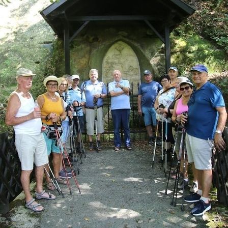 Eine Gruppe von Wanderern posiert für ein Foto vor einer kleinen Kapelle mit einem Hirschkopf auf dem Dach.