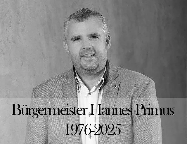 Ein Schwarz-Weiß-Porträt eines Mannes namens Hannes Primus, der Bürgermeister ist. Unter seinem Namen sind die Jahre 1976-2025 angegeben.