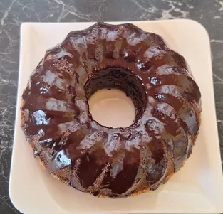 Ein Schokoladen-Gugelhupf auf einem weißen Teller auf einer Marmoroberfläche.