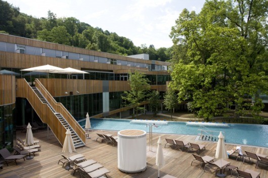 Ein großes modernes Resortgebäude hat einen großen Pool mit Liegestühlen und Sonnenschirmen.