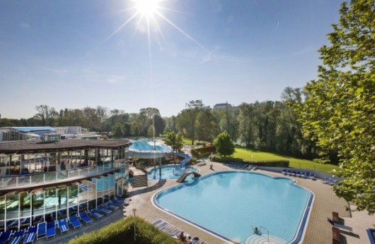 Ein Blick von oben auf ein Resort mit einem großen Pool, Wasserrutsche und sonnendurchfluteten blauen Himmel.