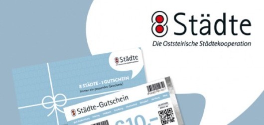 Eine Werbung für einen Geschenkgutschein der Osterreichische Stadtekooporation. Die Karte zeigt ein blaues Band, einen QR-Code und den Text 'Städte' mit dem Wert 'C10'.