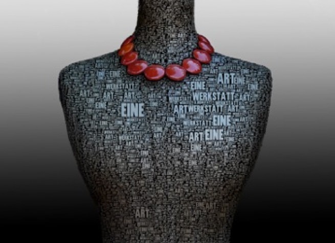 Ein Mannequin-Oberkörper zeigt eine Halskette aus roten Perlen. Der Oberkörper ist mit einer Mosaik aus Wörtern texturiert, darunter 'ART', 'EIN' und 'EINER'. Der Hintergrund ist grau.