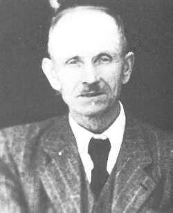 Ein altes Schwarz-Weiß-Porträt eines Mannes mit Schnurrbart, der einen formellen Anzug mit Krawatte trägt.